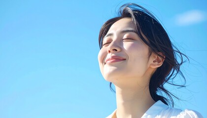 快晴の中で髪を風になびかせた若い日本人女性,A young Japanese woman with her hair blowing in the wind under a clear blue sky.