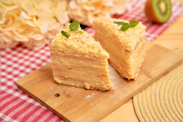 Delicious napolean cake slices on wooden board with floral and kiwi accents