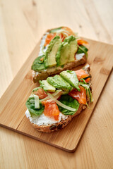Delicious smoked salmon avocado toast with spinach on wooden board