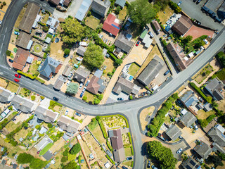 Aerial top down view of a parched lawns and vegetation seen in a town within the UK. Houses can be seen in rows along the empty street due to extreme summer weather of 2025.