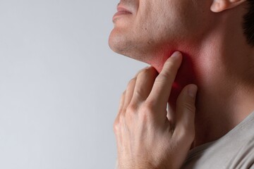 Man touching his throat, showing signs of discomfort with red and raw appearance. expression conveys pain and irritation, highlighting struggle with throat issues