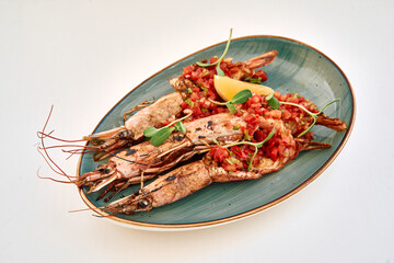 Grilled shrimp with tomato salsa and lemon on blue oval plate