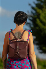 A woman with a beautifully designed tattoo on her back is walking down the street while carrying a...