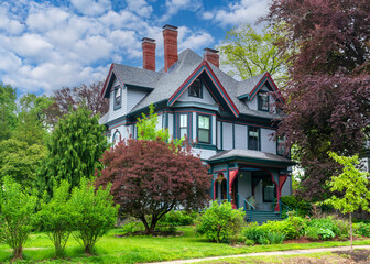 Stunning Queen Anne Victorian home with red trim and lush landscape in Newton, Massachusetts, USA