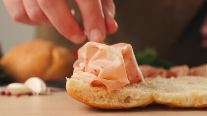 Mortadella ham sandwich, Traditional italian focaccia filled with thin pesto slices of mortadella, served by chef man in cafe restaurant. Macro of traditional italian spanish tapas antipasti.  - Powered by Adobe