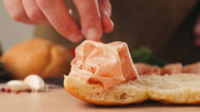 Mortadella ham sandwich, Traditional italian focaccia filled with thin pesto slices of mortadella, served by chef man in cafe restaurant. Macro of traditional italian spanish tapas antipasti. 