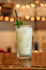 Refreshing mint iced drink on rustic bar table with bokeh background