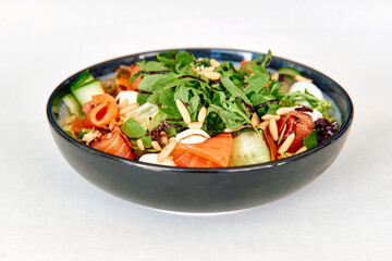 Fresh arugula and smoked salmon salad with cucumber, goat cheese, and pine nuts