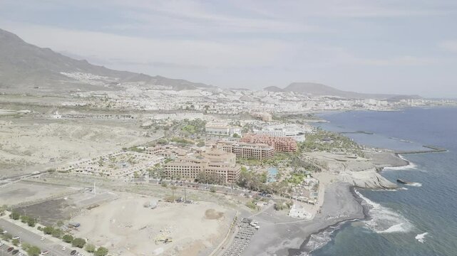 Drone flies south along coast over Playa El Beril beach in Costa Adeje, Tenerife, Canary Islands, Spain