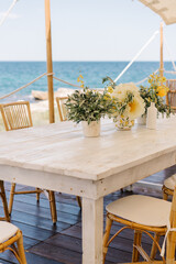 table and chairs on the beach, Event or wedding decoration with lemons and yellow flowers, outdoor event at the seaside