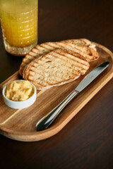 Grilled bread slices with butter and orange juice on wooden table
