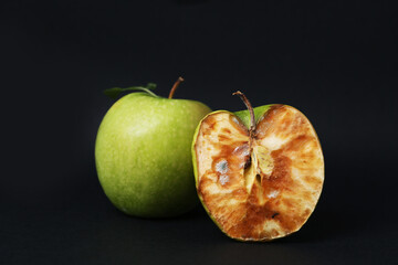 Spoiled apple and good ones on black background
