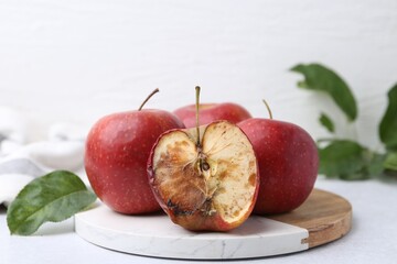Spoiled apple and good ones on white table, closeup