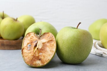 Spoiled apple and good ones on grey table, closeup