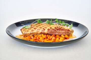 Grilled chicken with cheese sauce on diced vegetables garnished with microgreens