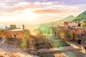 Obraz premium beautiful sunset landscape of evening ancient teatre of Taormina, Sicily in Italy with cityscape and evening mopuntains on background. Ancient archeological landscape of Italy