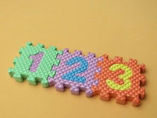Multicolored eva foam numbers puzzle on beige background. Education background. Math background.