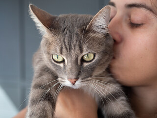Femme embrassant son chat gris avec tendresse
