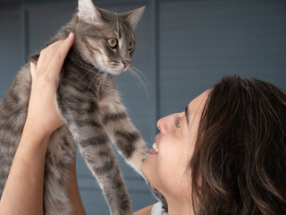 Femme tenant son chat dans les airs avec tendresse et amour
