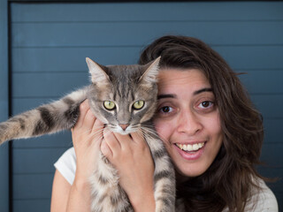 Femme souriante tenant un chat gris pr&egrave;s de son visage
