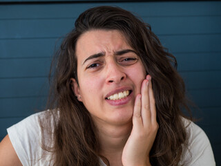 Femme brune avec douleur dentaire, main sur la joue