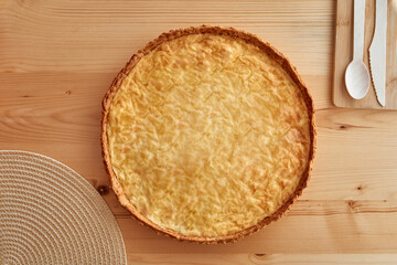 Golden apple pie on wooden table with rustic spoon and woven placemat