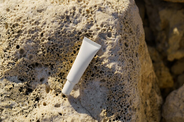 White thin mockup tube of cream on a stone by the sea. Concept of natural cosmetics for facial skin care, beauty products, sunscreen.