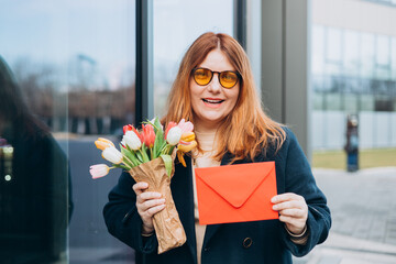 Portrait of nice attractive lovely pretty cheerful woman getting receiving congrats card greetings and big bouquet flowers, outdoors