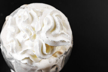 Whipped cream is squeezed out of a can onto a rotating cup of coffee on a black