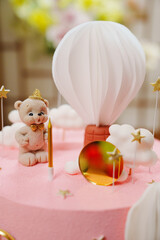 Pink cake with a decor of bears, balloons and clouds for the girl's birthday.