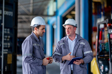 Colleagues in industrial environment talking beside delivery vehicle and storage aisle. Freight discussion and warehouse logistics workflow.