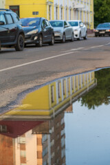 A city street with a  puddle of water , reflecting the surrounding buildings .