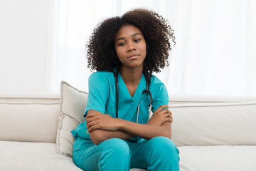 Stressed female doctor sitting on sofa while working in hospital. Tired female nurse in office at...
