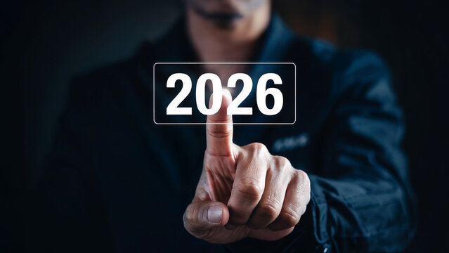 Person s finger touching a digital screen displaying the year twenty twenty six