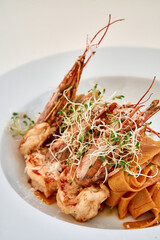 Gourmet shrimp pasta with sprouts and seasoning garnished in elegant presentation
