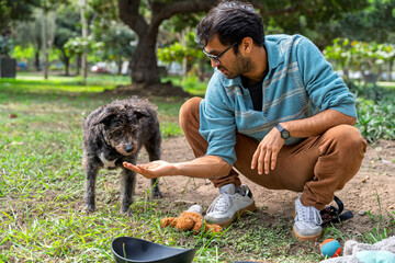Man feeding his mixed breed dog in park