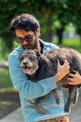 Man holding his mixed breed dog in a park