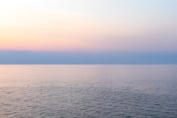 calm sea under pastel sunset sky. smooth water surface with warm tones and gentle light. minimalistic seascape background with clean