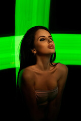 woman with long hair poses serenely as vibrant green light creates an engaging cross pattern behind...