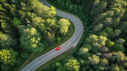 Heavy traffic of cars moves along a winding road through a green mountain landscape under a vast sky
