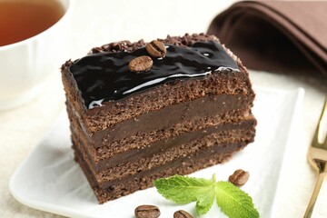 Piece of chocolate cake served with mint on white table, closeup
