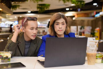 Gender diverse coworker business team eating salad and working digitally