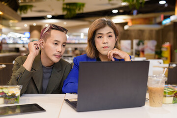 Gender diverse coworker business team eating salad and working digitally
