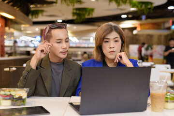Gender diverse coworker business team eating salad and working digitally