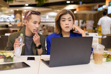 Gender diverse coworker business team eating salad and working digitally