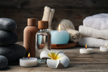 Composition with cosmetic products and spa stones on wooden table, closeup