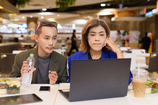 Gender diverse coworker business team eating salad and working digitally
