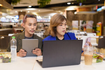 Gender diverse coworker business team eating salad and working digitally