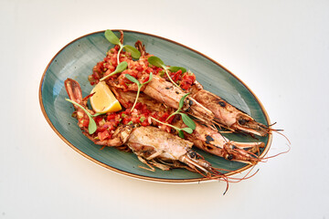 Grilled prawns with tomato salsa and lemon garnish on green plate