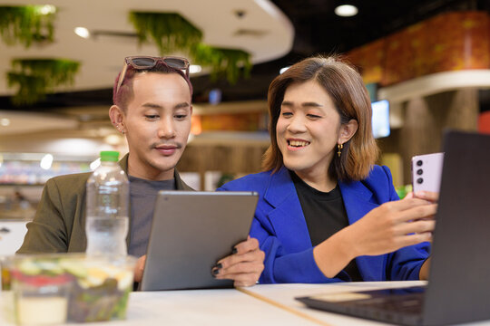 Gender diverse coworker business team eating salad and working digitally